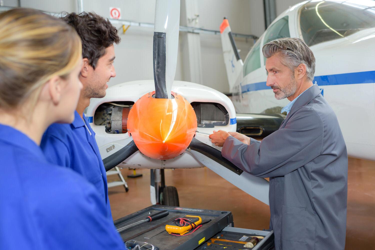 Two mechanics and a buyer inspecting a propeller